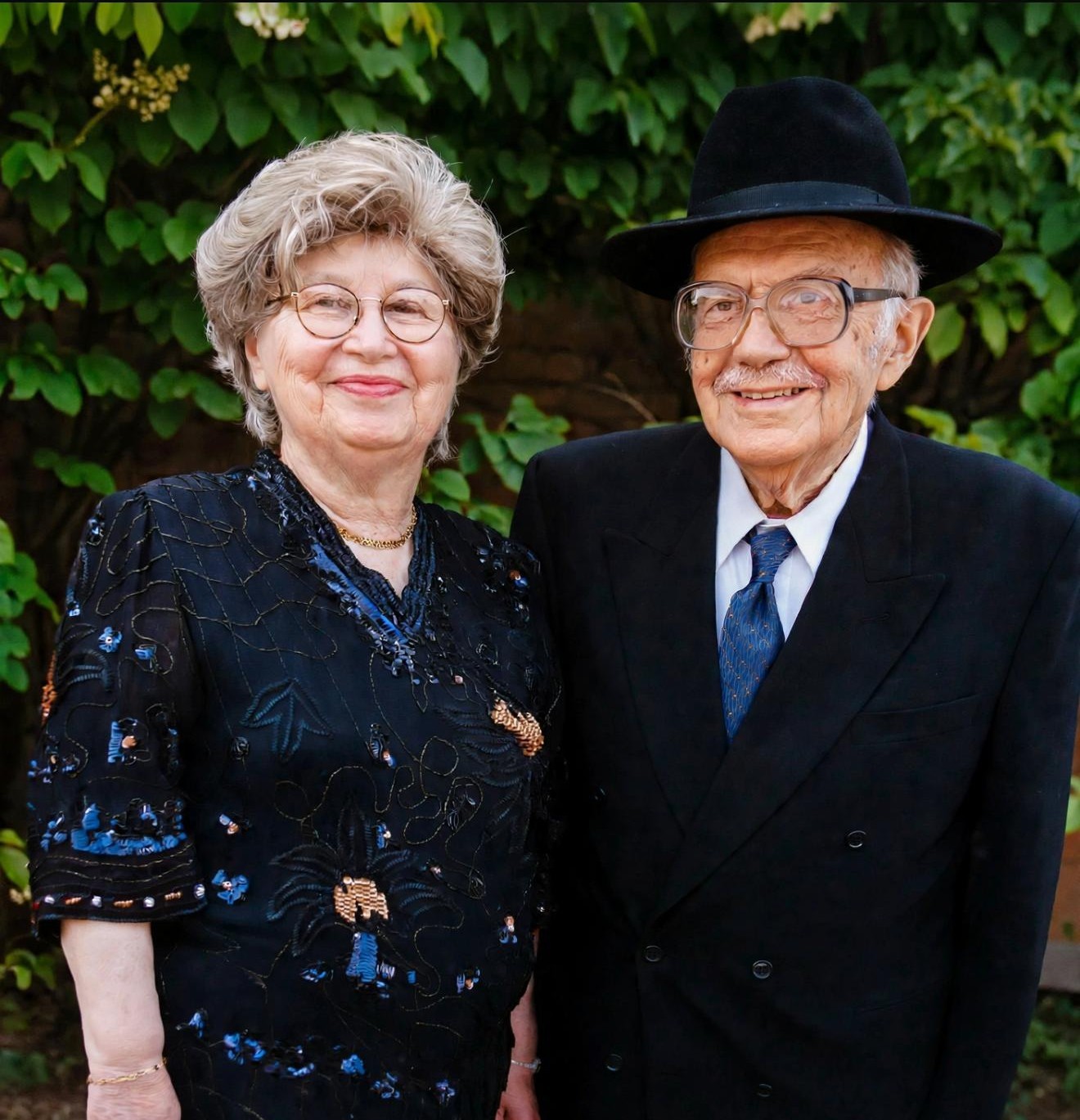 Bobby and Zeidy Rubenstein smiling together in front of green foliage