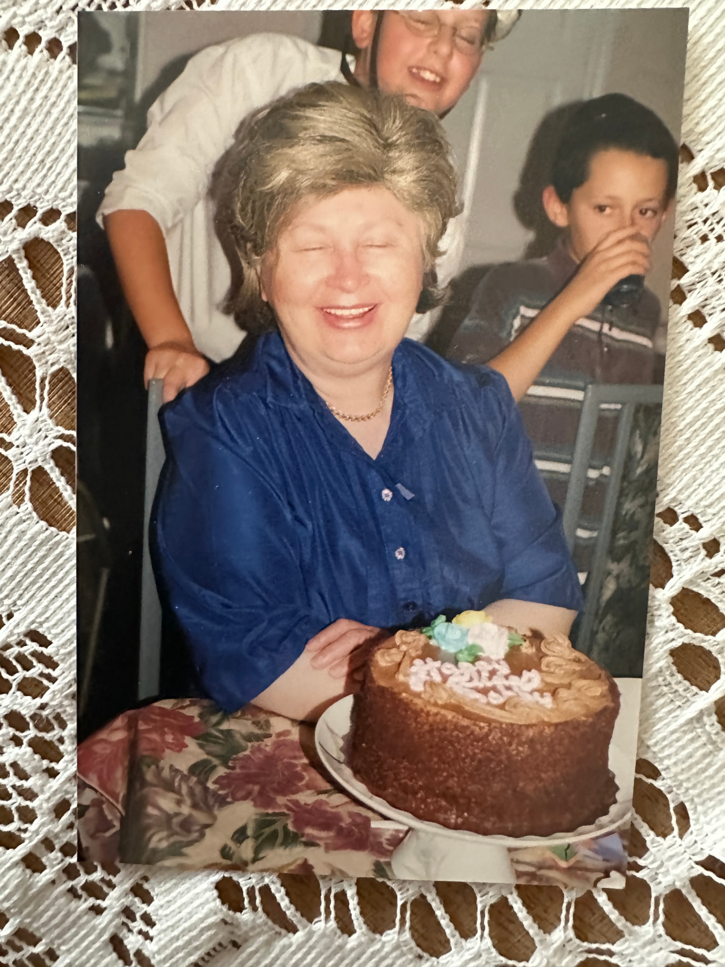 Bobby laughing over her birthday cake as the grandchildren crowd in