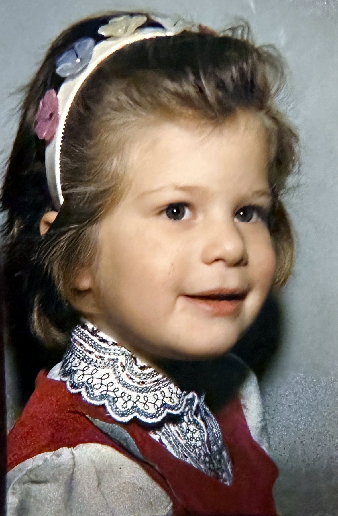 A young Rubenstein daughter in a red jumper and flowered headband
