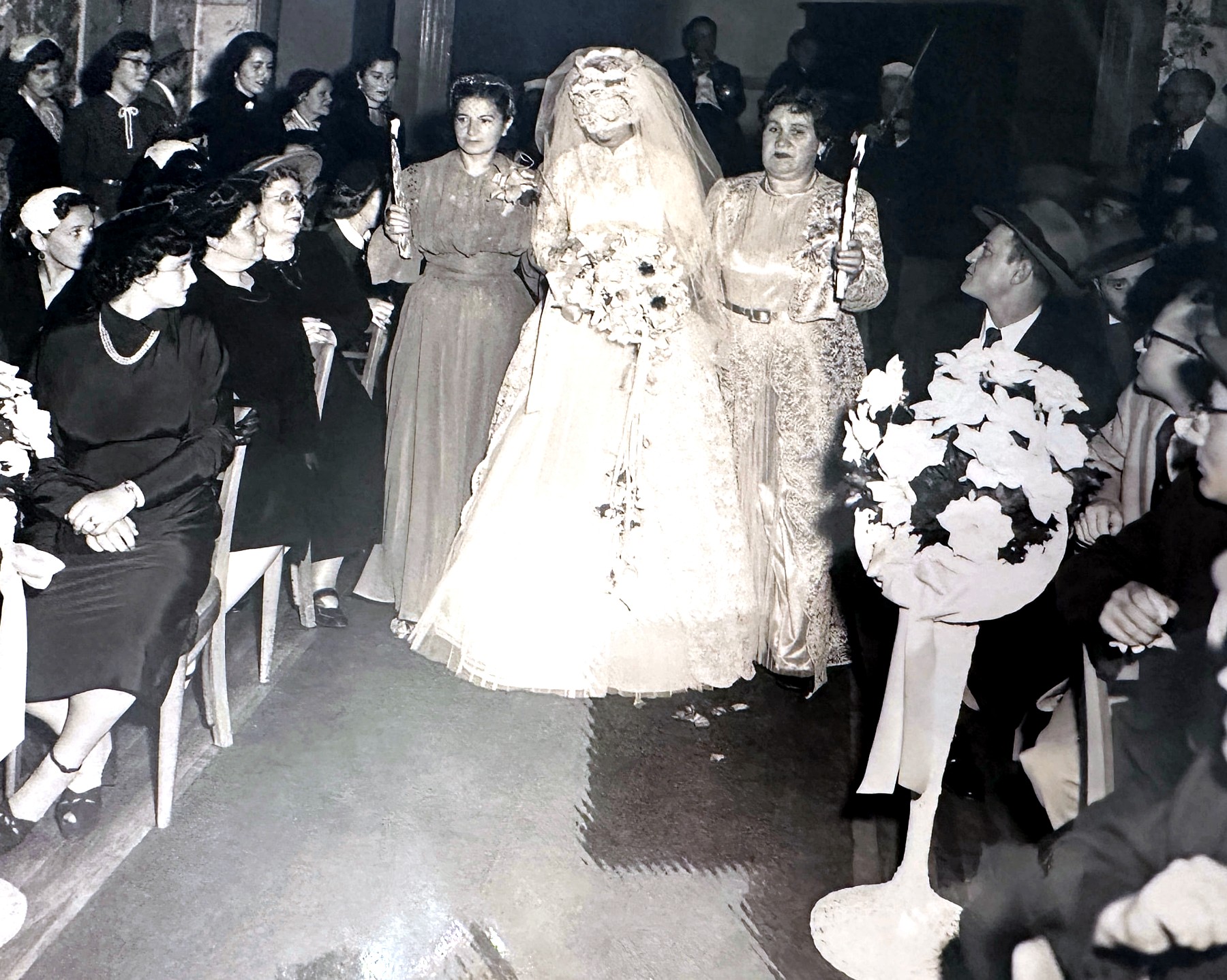 Esther being escorted down the aisle by candlelight as the guests look on