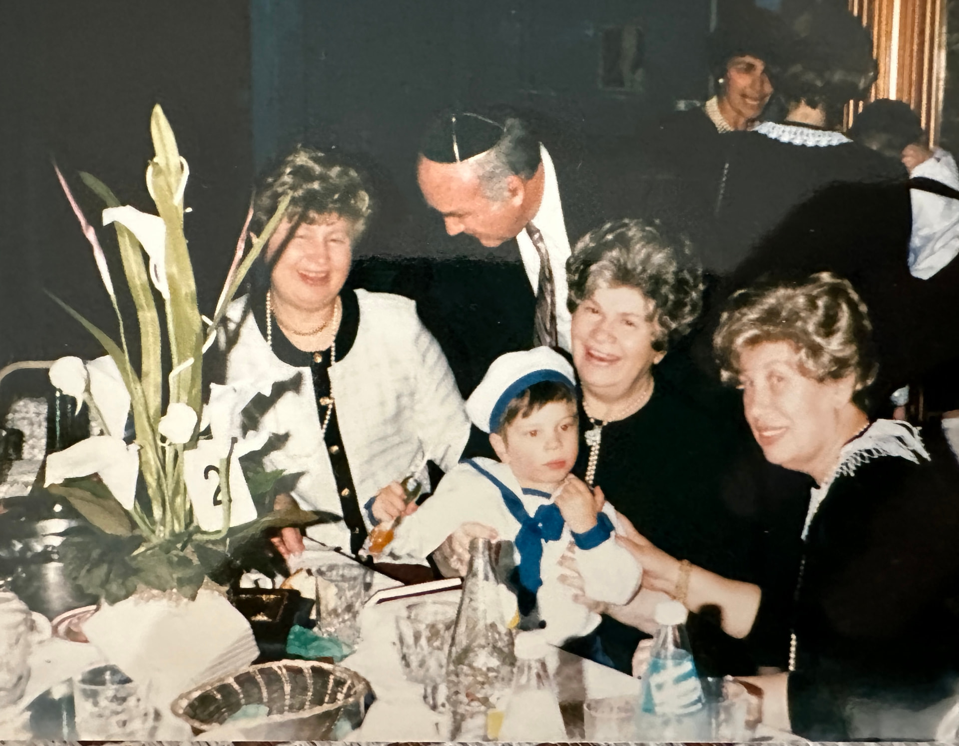 Bobby at a simcha table holding a little one in a sailor suit