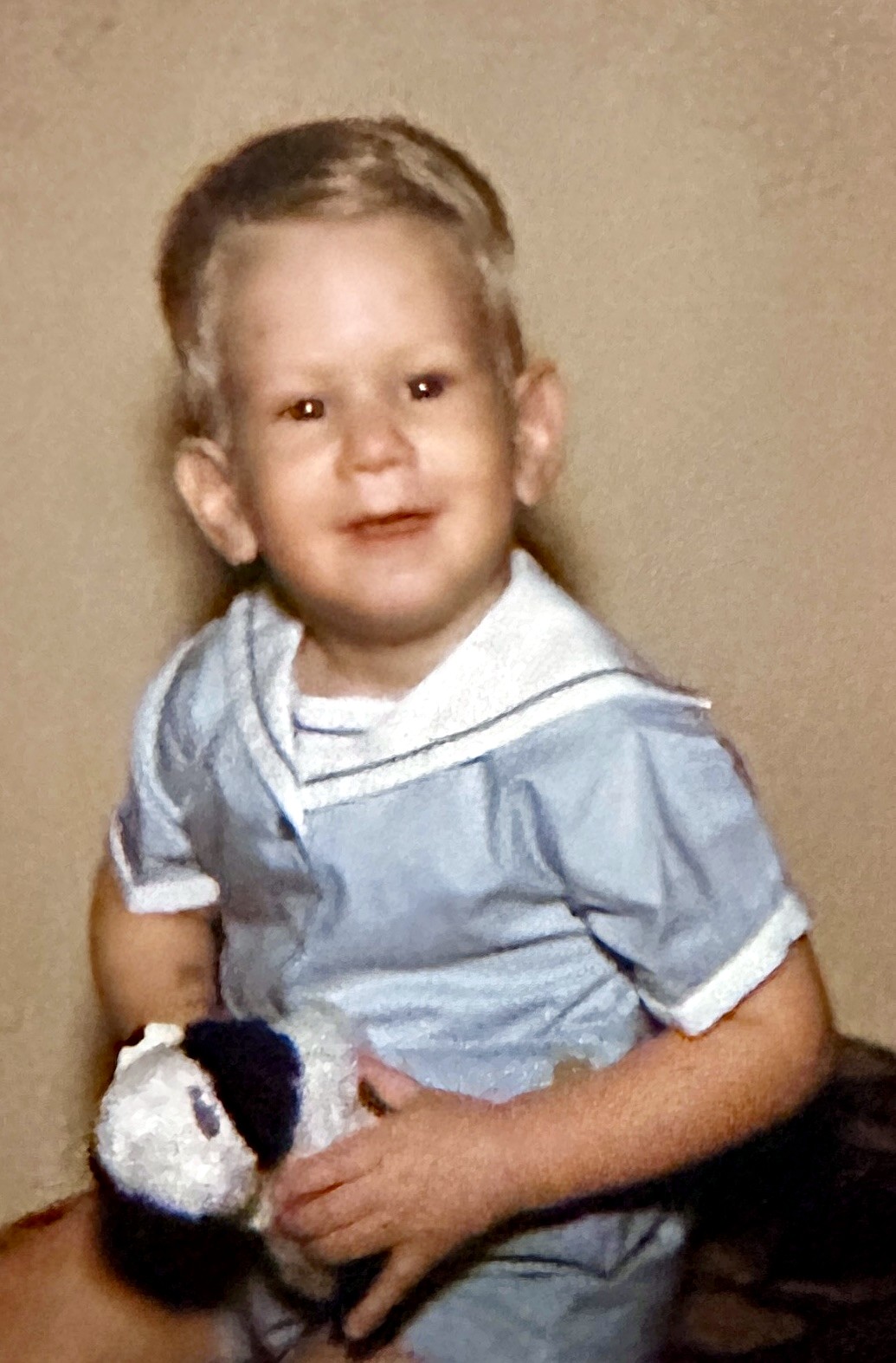 A little Rubenstein boy in a blue sailor outfit holding a toy
