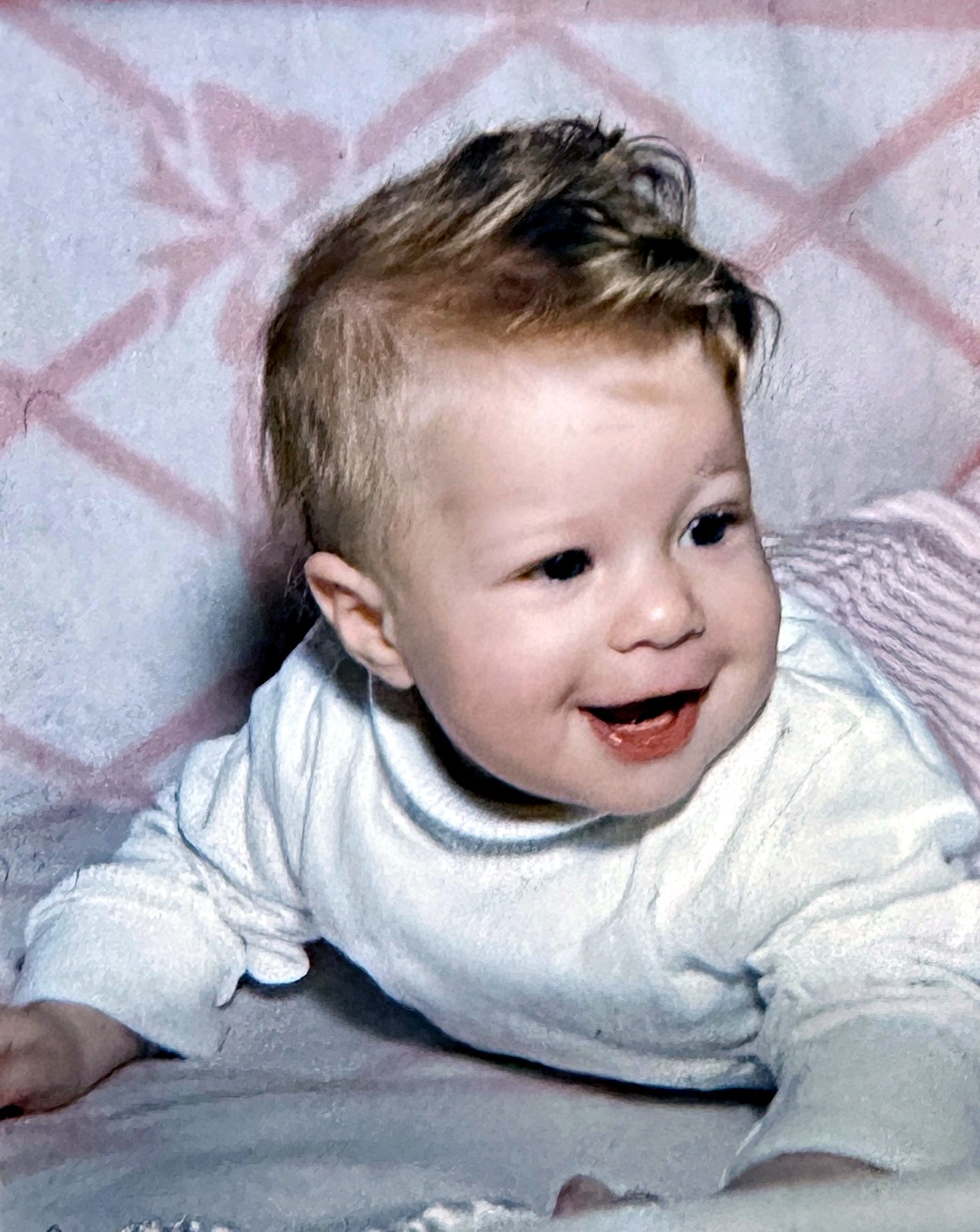 A Rubenstein baby laughing on a pink blanket