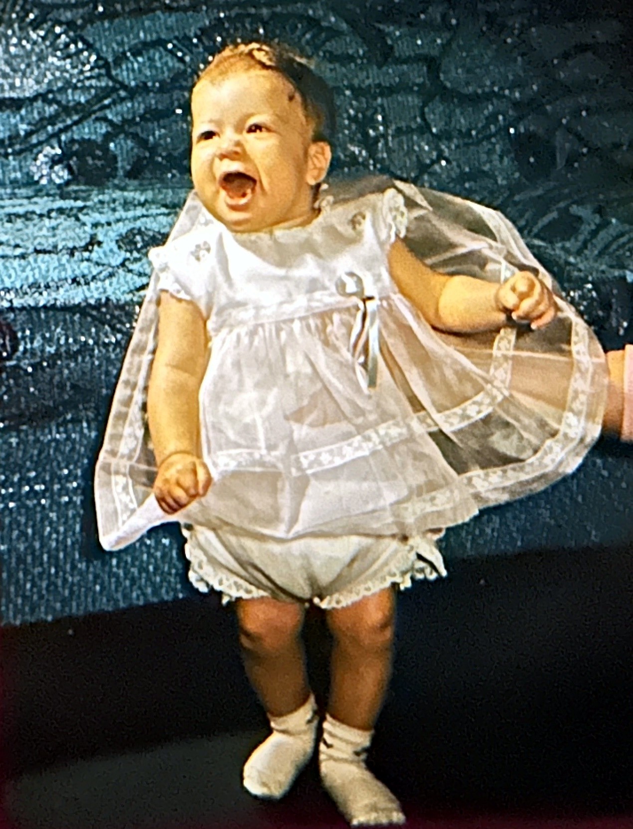 A Rubenstein baby girl laughing in a lace dress